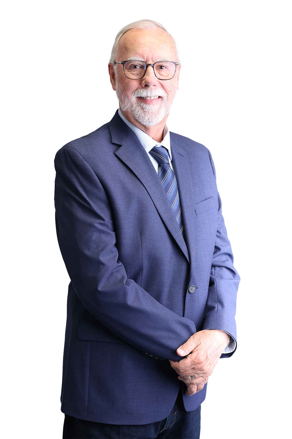 Elderly man with glasses smiling warmly, wearing a dark blue suit and tie, stands against a plain white background, exuding professionalism and warmth.