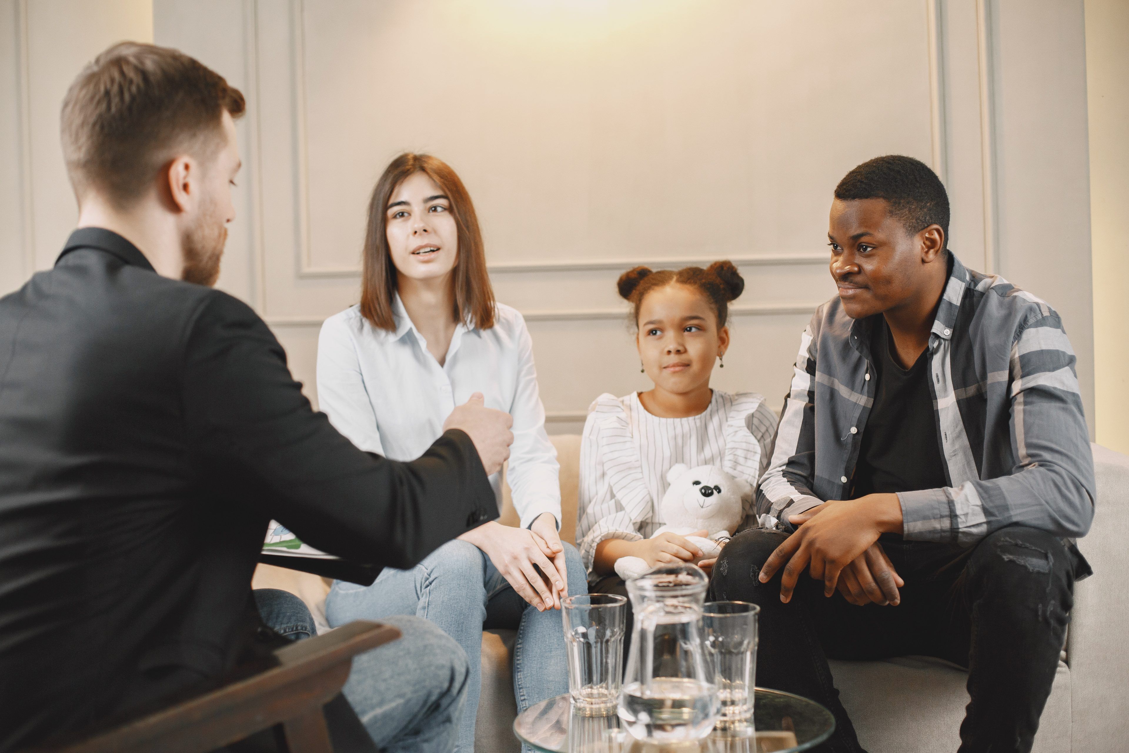 Family counseling session at home with therapist. Pshycologist showing pictures of emotions to a girL.African American father and European mother.