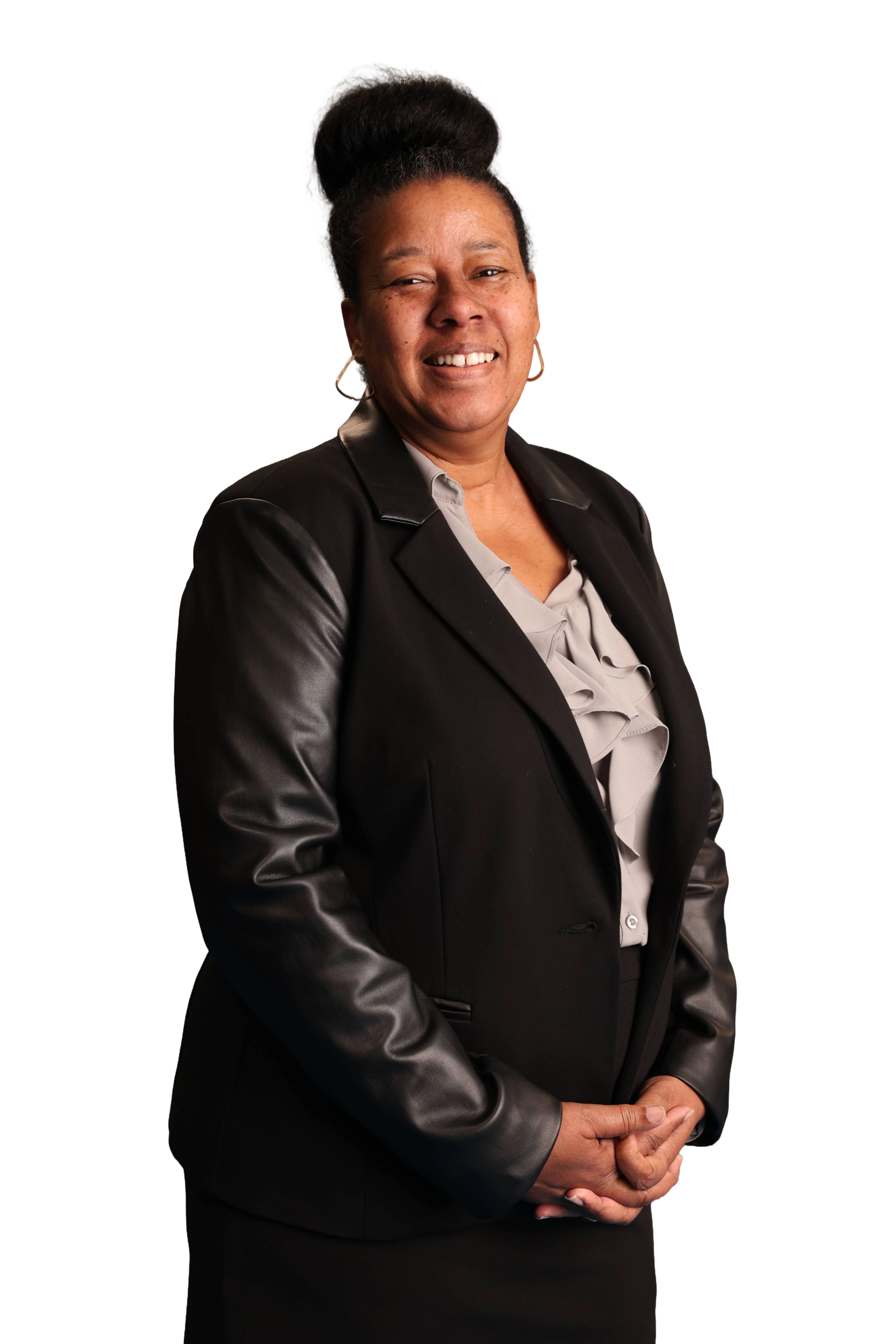 A smiling woman wearing a black blazer with leather sleeves and a gray blouse stands against a white background, conveying confidence and warmth.